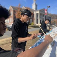 Seniors paint the rock on the George F. Baker lawn.