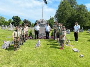Boys Scouts and American legion members team up to adorn veteran graves with flags.