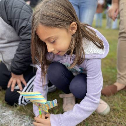 A student places a pinwheel of peace in the school lawn.