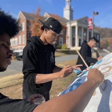 Seniors paint the rock on the George F. Baker lawn.