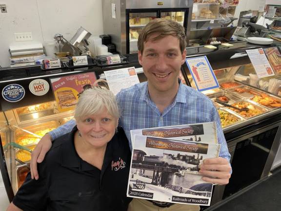 Woodbury Historical Society President Alex Prizgintas holds the 2025 calendar, with Colleen Pearce of Jay’s Deli.