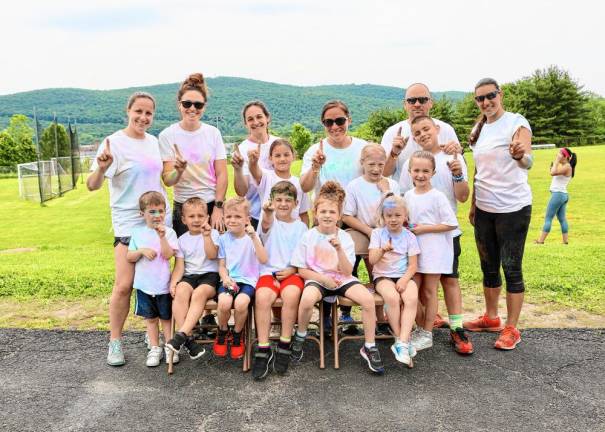 A group young runners and their parents celebrate after the finish of the color run