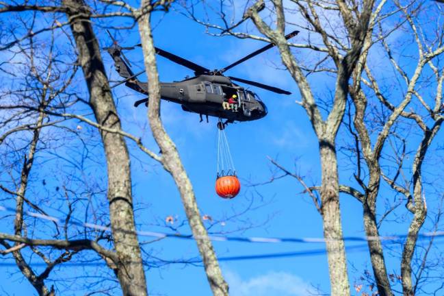 A helicopter prepares to douse the flames with water.