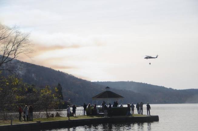 A crowd watches as one of the helicopters in use hauls water to the Jennings Creek Fire on Nov. 17.