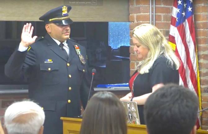 Woodbury Town Clerk Desiree Potvin administers the oath of office to Michael Faravashi of the Woodbury Police Department, who was promoted to the position of sergeant.
