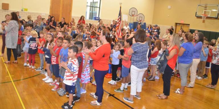 Elementary school students and teachers clap for the police officers, members of the fire department, American Legion, ambulance corps, local EMS and special guests.